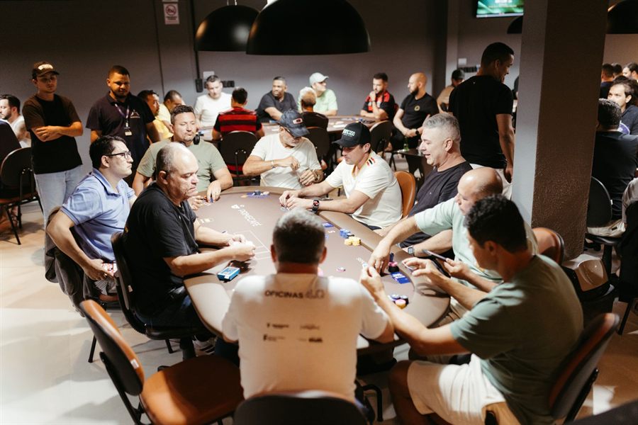 A busy poker room with players seated around several tournament tables